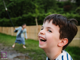 Young Boy Laughs As Sister Balances During Outdoor Play In Brittany A young boy laughs joyfully in the foreground as his sister tries to keep her balance outdoors in Brittany, France.