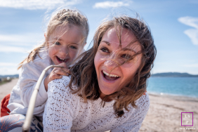 Mother And Daughter Laugh Together During Windy Beach Outing In Hyères A mother and daughter laugh together as the wind blows their hair during a playful beach outing in Hyères, Var, France.