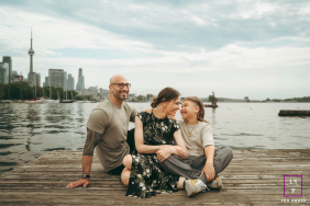 Family Spends Time Together On Waterfront Dock Overlooking Toronto Skyline A family shares time together on a waterfront dock with the Toronto skyline rising behind them.