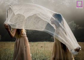 Two Cousins Play Beneath Flowing Fabric In Sunlit Woodstock Vermont Field Two cousins play beneath flowing sheer fabric as warm sunlight filters across a grassy field during an afternoon in Woodstock, Vermont.