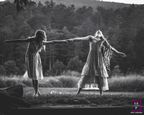 Two Girls Hold Hands Playing Freely In Woodstock Vermont Field Two girls hold hands and play freely in a field, their movement creating an expressive black and white scene in Woodstock, Vermont.