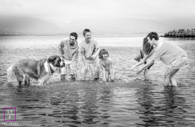 Family And Dog Play Together In Shallow Waters At Chéticamp, Nova Scotia A family and their dog play together in the shallow bay waters during a relaxed outdoor family session in Chéticamp, Nova Scotia, Canada.