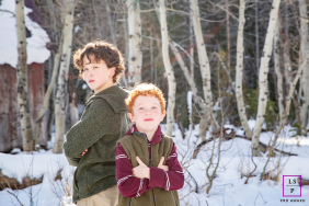 Two Brothers Pose Playfully Among Snowy Trees In Truckee California Two brothers stand with arms crossed among snowy trees, sharing a playful moment during a winter family session in Truckee, California.