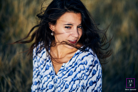 A woman stands outdoors as the wind sweeps through her hair, creating a quiet, reflective expression in La Tranche-sur-Mer, France.