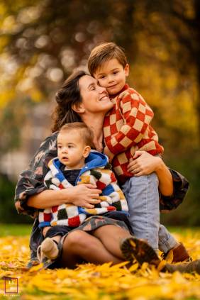 Mother Cuddles Two Young Sons Among Autumn Leaves In Dordrecht A mother cuddles her two young sons among fallen autumn leaves, sharing a tender family session together in Dordrecht, the Netherlands.