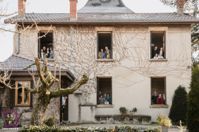 Multigenerational Family Gathers In Home Windows During Winter In Caluire-et-Cuire A multigenerational family gathers in separate windows of their family home during a winter lifestyle session in Caluire-et-Cuire, Rhône, France.