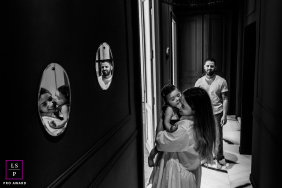 Mother Kisses Young Daughter As Father Follows Through Sète Hallway A mother carries and kisses her young daughter as the father follows through their hallway, reflected in mirrors in Sète, France.