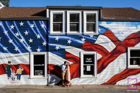 A couple stands closely together beneath a colorful American flag mural during a relaxed lifestyle session in Los Gatos, California.