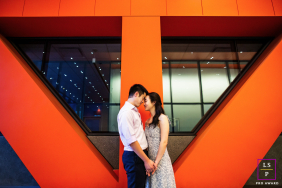 A couple holds hands and leans together beneath bold geometric architecture during a relaxed lifestyle session at Stanford University in California.