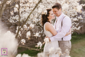 A couple stands closely embraced among flowering bushes, surrounded by lush greenery at Rittergut Störmede in Geseke, Germany.