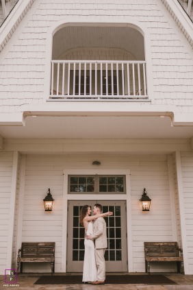 A young couple embraces beneath the entrance of a white home, sharing a quiet affectionate session together in Bergen County, New Jersey.
