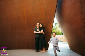Child Runs Playfully As Parents Embrace At Stanford University California A child runs playfully in front of his parents as they embrace beside striking modern architecture at Stanford University in California.