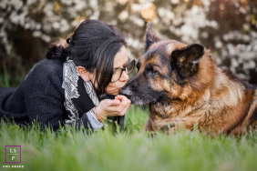 A woman shares a tender connection with her elderly German Shepherd as they rest together in the grass in Lyon, France.