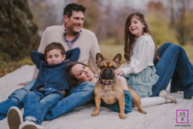 A family relaxes together on a blanket while their French Bulldog stands proudly at the center in Bergen County, New Jersey.