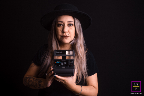 Um fotógrafo de estilo de vida tirou uma foto de Andreza Cavalcanti Fotografia em São Paulo, Brasil, mostrando-a calma e confortável segurando uma câmera Polaroid.