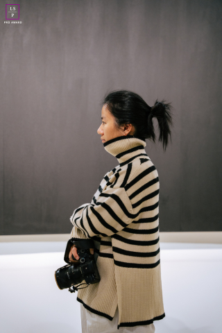 Photographer Ann Zhang in a museum in New York City, holding her camera by her side