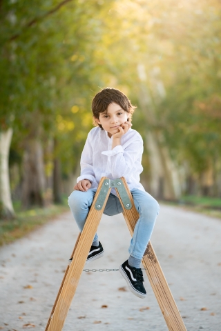 Mode de vie créatif de Madrid Portrait d'enfant sur une échelle à l'extérieur sur une chaussée bordée d'arbres