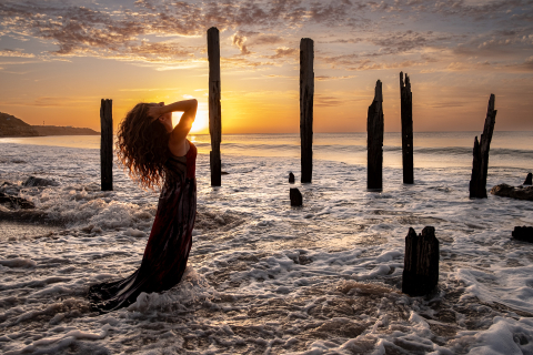 A stunning amalgamation of nature and human form, this lifestyle portrait captures a woman in complete harmony with her surroundings. Against the breathtaking backdrop of Port Willunga, South Australia, she stands alone at the pier pilon ruins.