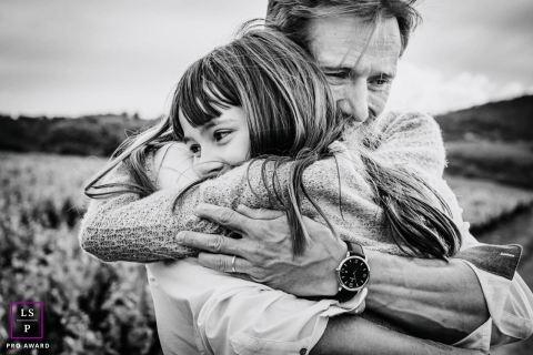 Auvergne-Rhone-Alpes father and daughter pose for a Lifestyle portrait as they embrace in a big hug