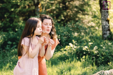 A lifestyle portrait showcases a mother and daughter in Redmond, WA, as they enjoy springtime together by blowing daffodils