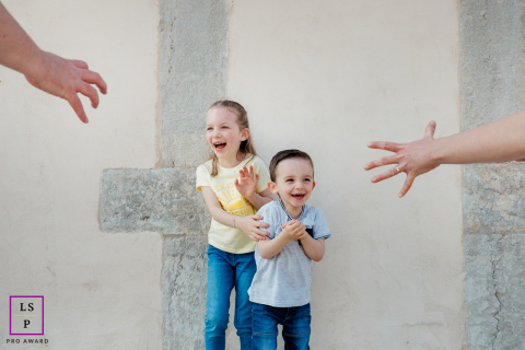 A playful family portrait session, capturing the joy of two siblings as their parents sneakily tickle, with only their hands visible.