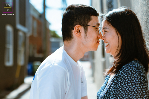 Une romance ensoleillée à Baltimore : un couple partage un moment de tendresse dans une ruelle Dans une ruelle de Baltimore, un couple touche tendrement leur nez tandis que le soleil illumine leur amour au milieu des rues de la ville.