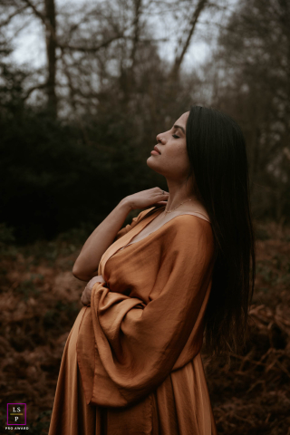 Dans un parc de Londres, une future maman rayonne dans une élégante robe en soie orange, alors qu'elle profite d'un moment de paix au milieu de la beauté naturelle de la ville.
