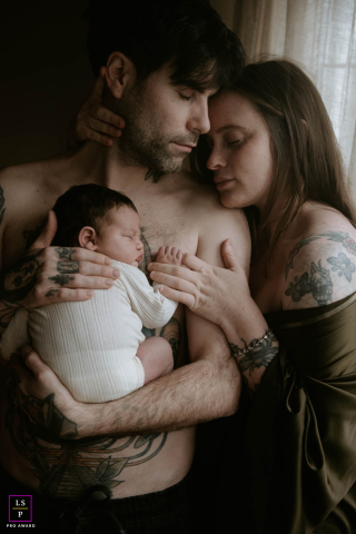 À Margate, en Angleterre, une famille de trois personnes partage un moment de tendresse à la maison. Le couple tient affectueusement son nouveau-né, les yeux fermés, savourant l'intimité tranquille et la chaleur de leur nouvelle vie ensemble.