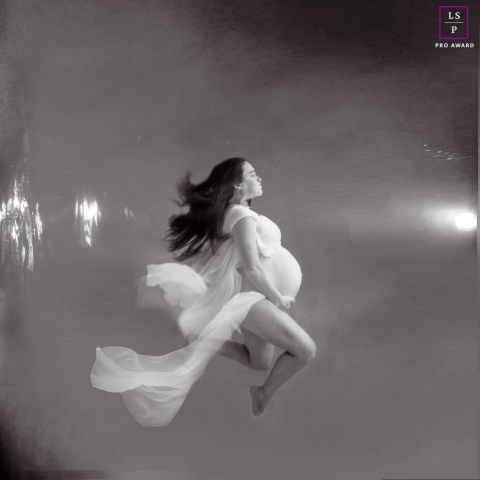 Attente éthérée : un portrait de maternité sous-marin à Sarasota Dans une piscine sereine à Sarasota, en Floride, une future maman pose gracieusement pour un portrait de maternité sous-marin, sa robe fluide et ses cheveux flottant doucement autour d'elle, créant une scène magique et éthérée.