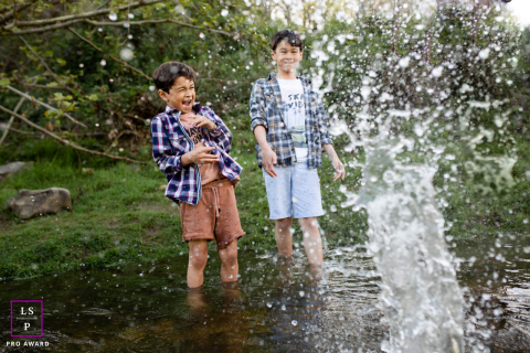 Eclaboussures de joie : Aventures d'enfance en Haute-Garonne Deux garçons pleins d'énergie lancent joyeusement des pierres et créent des éclaboussures dans les eaux peu profondes de la Haute-Garonne. Un style de vie insouciant et joyeux est capturé dans ce portrait vibrant.