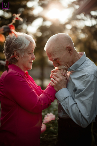 Timeless Devotion: Forty Years of Love in Mahomet A couple in Mahomet, IL, in the US, standing close together as the man tenderly holds the woman's hand and kisses it. They have been together for forty years, their love evident in this intimate and heartwarming lifestyle portrait.