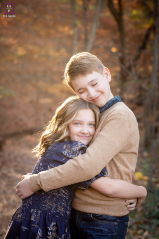A heartwarming scene of a young brother and sister embracing near a wooded area in Washington, DC, surrounded by the colors of fall.