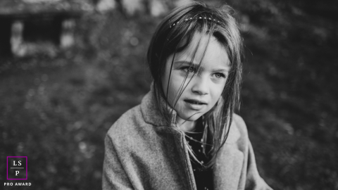 In Firenze, Toscana, Italia, a black and white portrait captures a young girl in a natural setting. The image highlights her serene expression and the timeless beauty of the surrounding landscape.