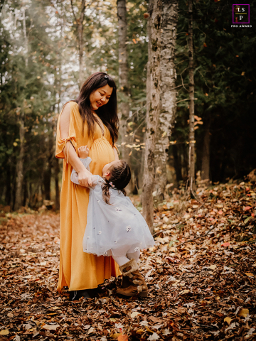 Nature's Embrace: Joyful Bonding Between Mother and Daughter in Ottawa's Forest Serenity In Ottawa, Ontario, Canada, a pregnant mother shares a tender session with her little girl in the forest. The scene reflects their joyful bond and the beauty of nature surrounding them.