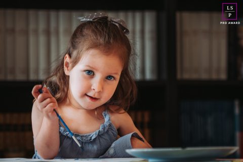 À Solliès, dans le Var, un portrait d'une petite fille est immortalisé alors qu'elle peint à la maison. L'image reflète sa concentration et sa créativité, mettant en lumière son exploration artistique.