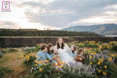 A loving mother in Mosier, Oregon, is surrounded by her five beautiful children, including the new addition to the family. She is smiling and embracing her children.
