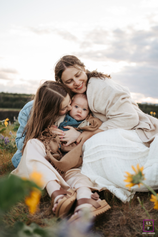 In Mosier, OR, a mom sits outdoors snuggling closely with her oldest and youngest children, sharing a warm, affectionate session surrounded by natural scenery.