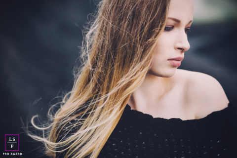 Em Hagen, Alemanha, uma jovem é retratada de perfil, com o cabelo suavemente espalhado pelo quadro, criando um elemento suave e dinâmico na composição do retrato.