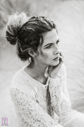 Close em preto e branco de uma jovem mulher sardenta em Nordwijk, Holanda. Ela veste roupas de renda branca, e suas características e texturas naturais são realçadas pela fotografia monocromática.