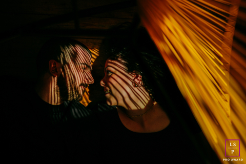 In Montpellier, France, a couple lies together in their apartment, sunlight and shadows playing across their faces as they gaze at each other.
