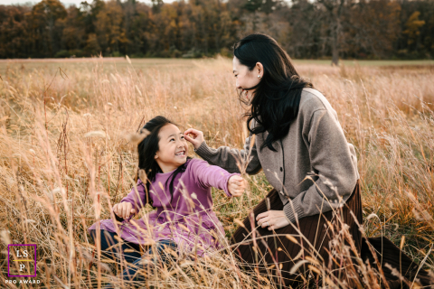 At Waveny Park in New Canaan, mom and daughter smile together while surrounded by tall, dry grass.