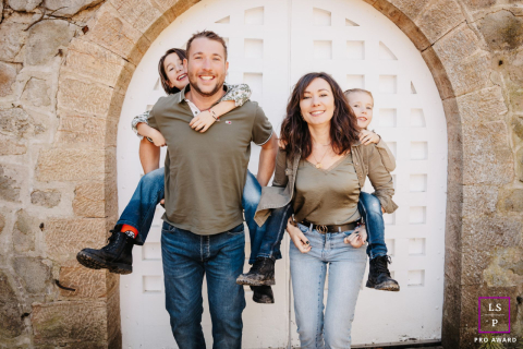 At Parc de Lacroix-Laval in Marcy l'Étoile, Rhône, parents give piggyback rides to their children, all four smiling at the camera.