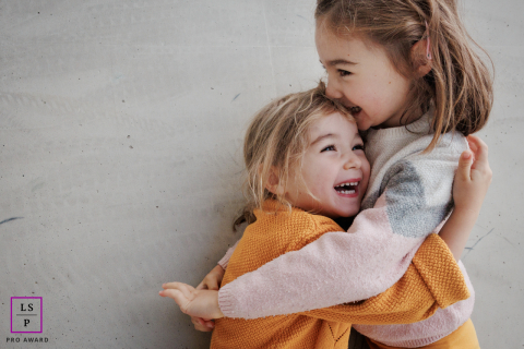 In Paris, sisters play together against an urban concrete backdrop, framed by minimalist surroundings.