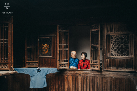 Older Chinese couple framed in a Boston window for the festive Chinese New Year.