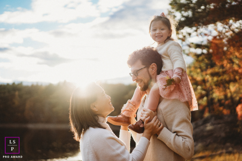 Family of three enjoys a sunny fall hike together at a Boston lakeside park.