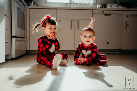 Boston lifestyle portrait showing shadow play with two siblings in buffalo red and black plaid pajamas.