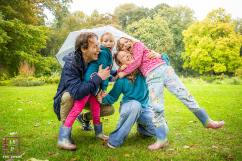 A family of four shares an umbrella and laughs joyfully as rain begins to fall in Utrecht.