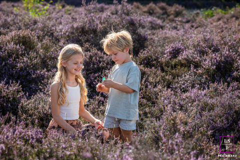 Brother and sister curiously inspect plants together on the Blaricum heath in The Netherlands.