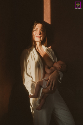 The Monaco photographer uses a sliver of golden light to carve this mother out of the shadows like a Renaissance painting. It is a masterfully quiet study of peace, devotion, and new life.