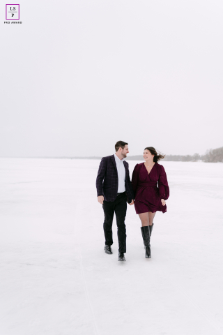 Couple Walks Across Frozen Lake In Appleton Surrounded By White Simplicity And Intimacy In Winter Across the frozen lake in Appleton, this couple walks through winter with smiles untouched by the bitter cold. The vast white space surrounding them gives the photograph simplicity, intimacy, and a wonderfully cinematic sense of isolation.